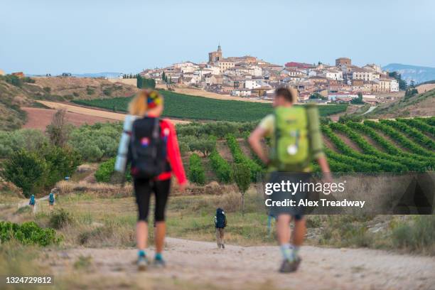 pilgrims hiking the trail called camino de santiago also known as the way towards the beautiful little village of cirauqui - santiago stock pictures, royalty-free photos & images