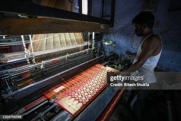 Worker uses a hand loom to weave a traditional Banarasi silk sari at a workshop as Uttar Pradesh, India's most populous state, re-opens on June 21,...