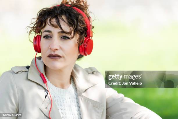 primer plano de la cara de una mujer muy guapa de pelo rizado que tiene sobre su cabeza unos auriculares rojos con cable. - primer plano stock-fotos und bilder