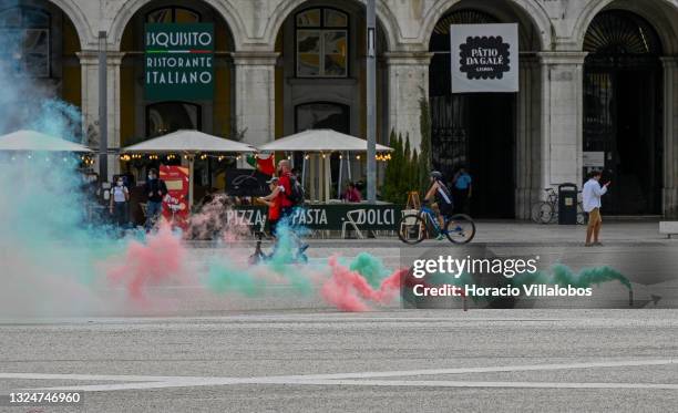 Tourists ride an e-scooter behind smoke grenades with the colors of the Portuguese flag lit by members of Portuguese security forces as they march...