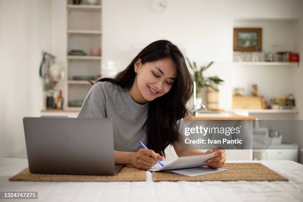 beautiful mongolian woman taking care of her finances at home - bill payment stock pictures, royalty-free photos & images