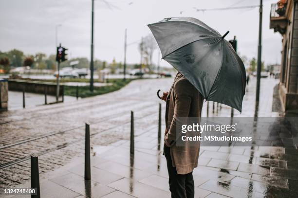 an unknown man stands with an open umbrella - man with umbrella stockfoto's en -beelden
