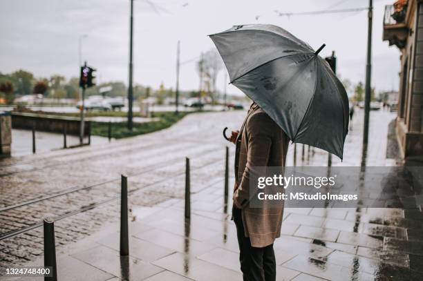 an unknown man stands with an open umbrella - umbrella bildbanksfoton och bilder