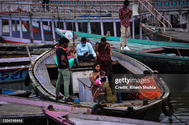 People sit on a boat as Uttar Pradesh, India's most populous state, re-opens on June 21, 2021 at the Dashashwmedh Ghat, along the banks of the Ganges...