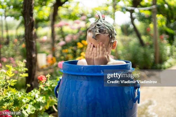 small boy taking bath in a water tank in the garden - een bad nemen stockfoto's en -beelden