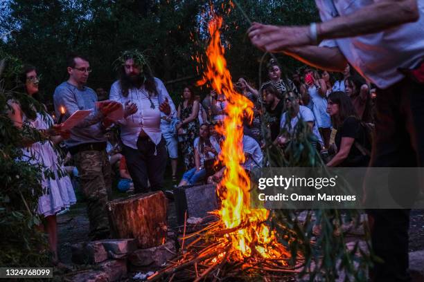 People wear flower crowns and hold candles around a bonfire during a Summer Solstice celebration on June 21, 2021 in Krakow, Poland. The summer...