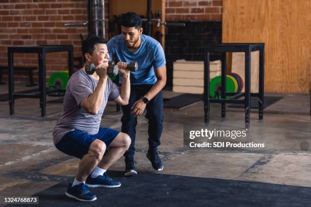 strong senior man uses hand weights - personal trainer stock pictures, royalty-free photos & images