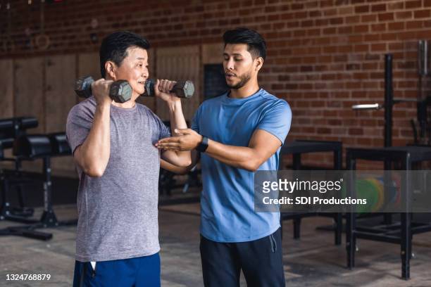 personal trainer helps senior man with weights - fitness personal trainer imagens e fotografias de stock