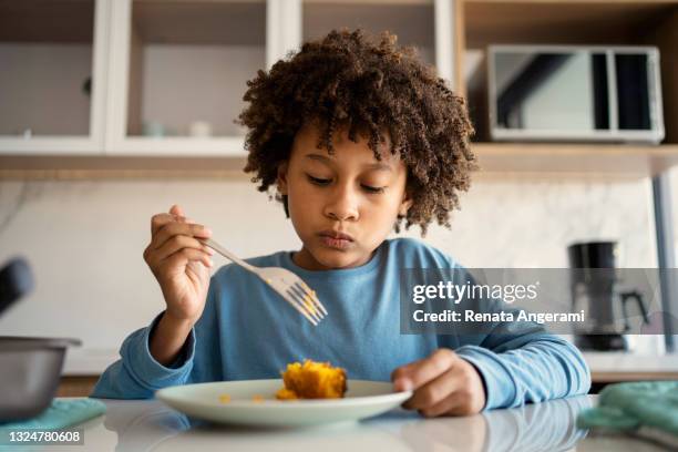 beautiful afro young boy eating cake at kitchen - kid eating stock pictures, royalty-free photos & images