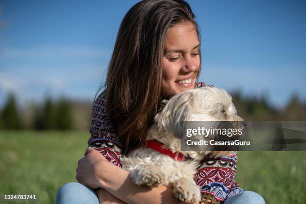 smiling young woman bonding with her dog in rural scene - maltese dog stock pictures, royalty-free photos & images