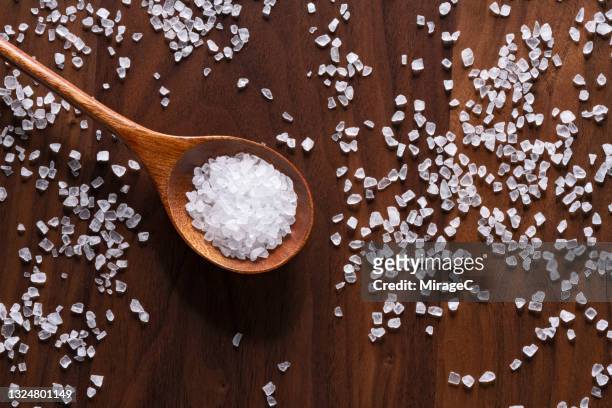 sea salt grains in wooden spoon - salt stock pictures, royalty-free photos & images