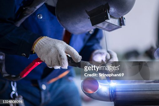 Welder is welding  the metal tube in the factory