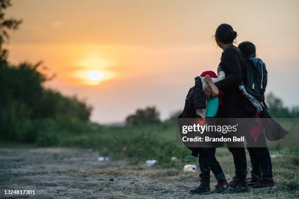 Migrant family watches the sunset while waiting to be accounted for and taken to a border patrol processing facility after crossing the Rio Grande...