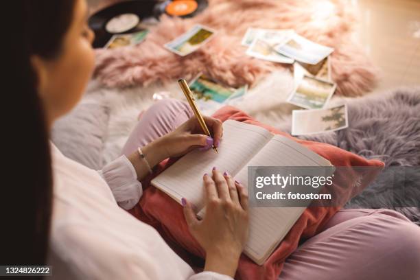 over the shoulder view of young woman writing in her diary - left hand stock pictures, royalty-free photos & images