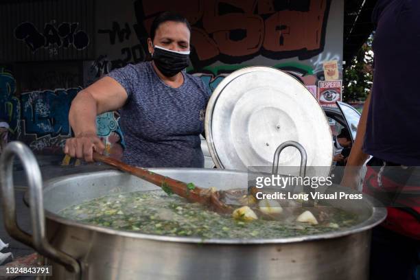 Woman prepares soup for people watching the concert Arte Unido x Colombia held at the Monumento a los Heroes, several urban music artists and Mc's...