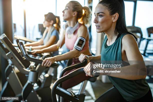 determined athletic woman having a stationary bike class in a gym. - stationary cycling class stock pictures, royalty-free photos & images