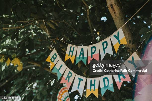 a 'happy birthday' banner hangs from a tree - happy birthday garden stockfoto's en -beelden