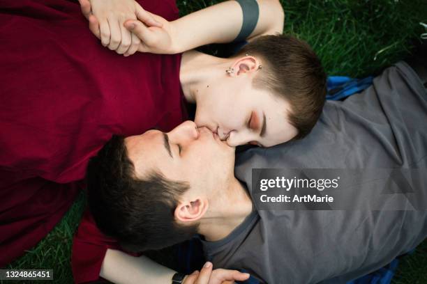 teenage couple laying on grass - kussen stockfoto's en -beelden