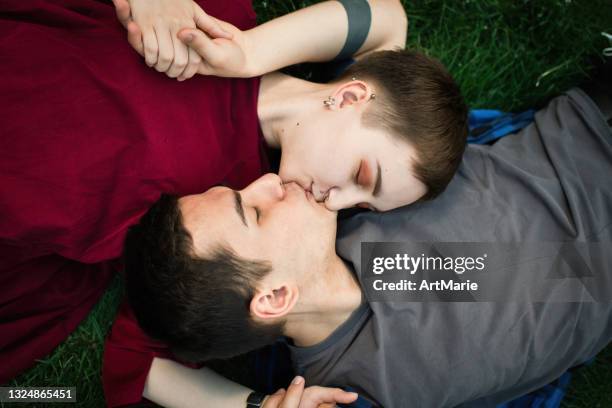 teenage couple laying on grass - teenagers kissing stock pictures, royalty-free photos & images