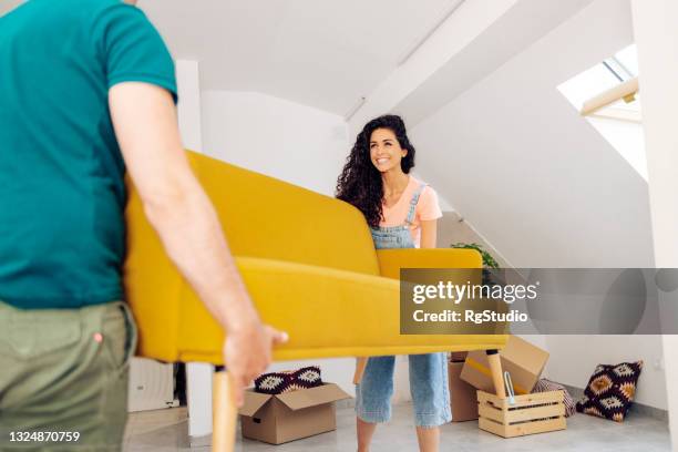 happy woman and her husband carrying sofa into their new house - carrying sofa stock pictures, royalty-free photos & images