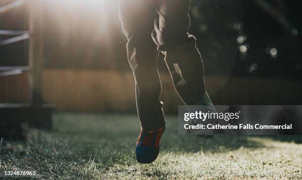 a child wearing school trousers and trainers plays outside - stomp stock pictures, royalty-free photos & images