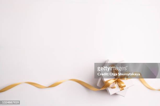 two white gift box with gold ribbon on white background, top view - gold satin ribon stock-fotos und bilder