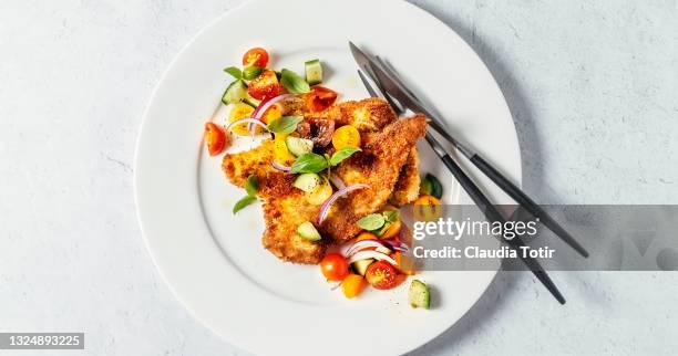 plate of schnitzel with salad on white background - chopped tomatoes foto e immagini stock