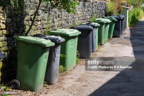 line of wheelie bins in a yorkshire village - green garbage bin stock pictures, royalty-free photos & images