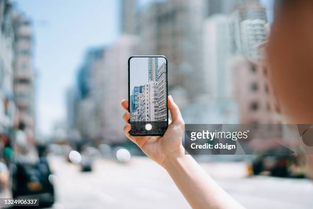 close up of woman's hand taking a photo of local city street view in hong kong with smartphone - photographing foto e immagini stock