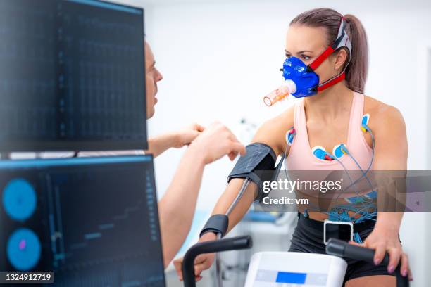 doctor talking to athlete before while preparing equipment for biometric testing - breath test stockfoto's en -beelden