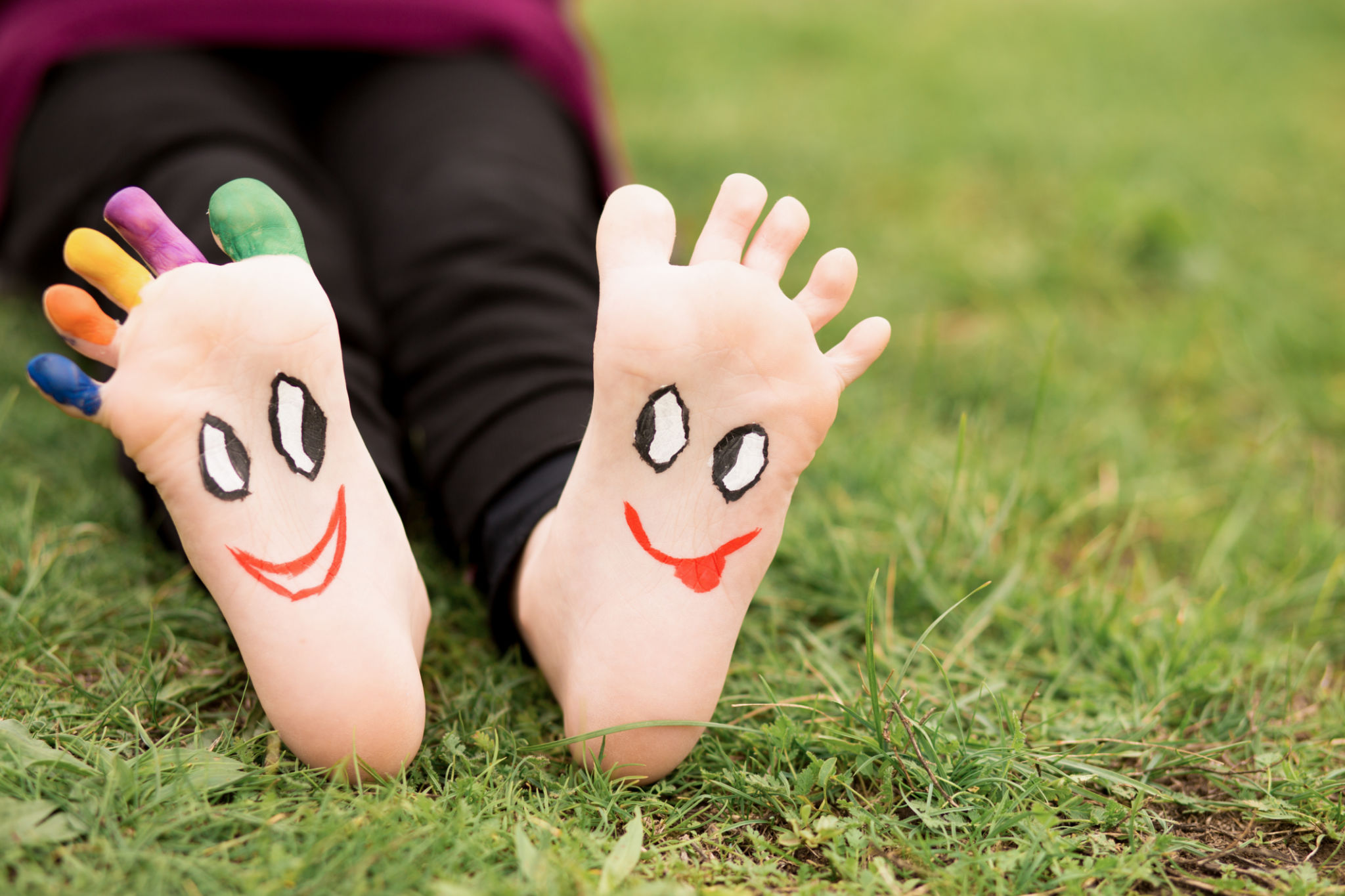 Child have fun outdoor on grass. Feet of child with painted faces. Child have fun outdoor on grass. Feet of child with painted faces.