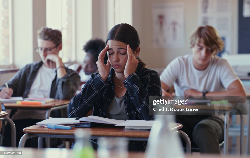 Shot of a student struggling with schoolwork in a classroom