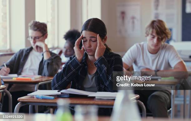 shot of a student struggling with schoolwork in a classroom - school exam stockfoto's en -beelden