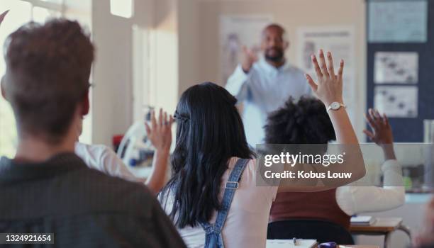 scatto di retrovisore di studenti che alzano la mano durante una lezione con un insegnante in classe - student high school foto e immagini stock