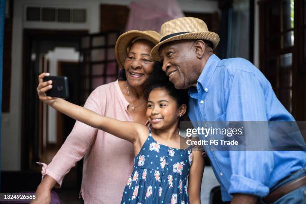 mädchen macht selfie mit großeltern während der ferien - besuch zuhause sommerlich innenaufnahme stock-fotos und bilder