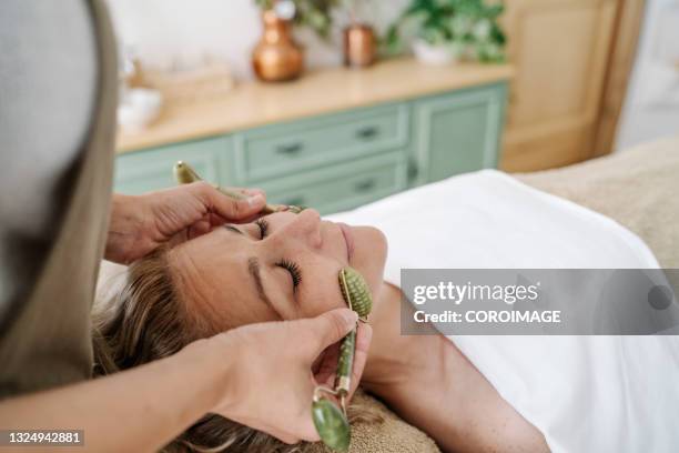 close-up view of physiotherapist doing massage with gemstone rollers to woman at beauty spa - woman facial expression stock pictures, royalty-free photos & images