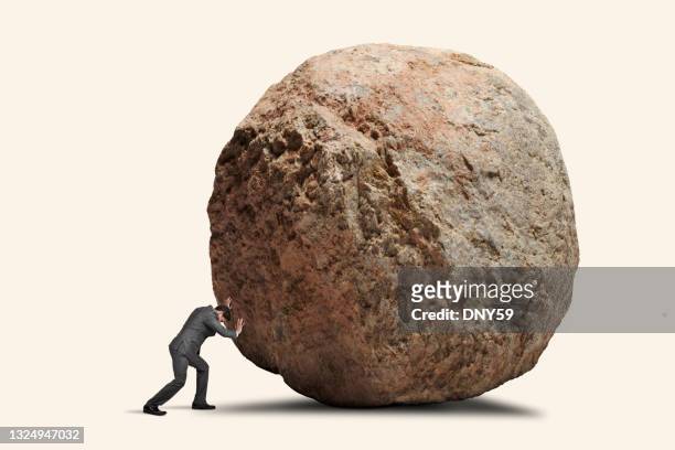 man attempts to push giant boulde - boulder rock stock pictures, royalty-free photos & images