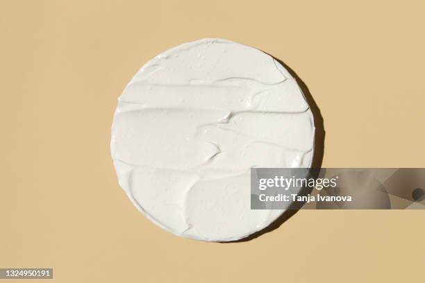 liquid textured white facial creamy cream isolated on beige background. - cream dairy product stock-fotos und bilder