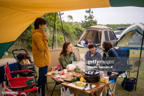 families eating foods and talking at camp - dekzeil stockfoto's en -beelden