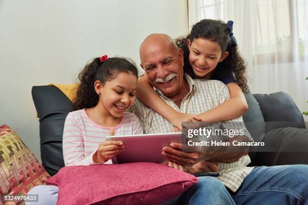 hispanic girls using digital tablet with her grandfather - musician computer stock pictures, royalty-free photos & images