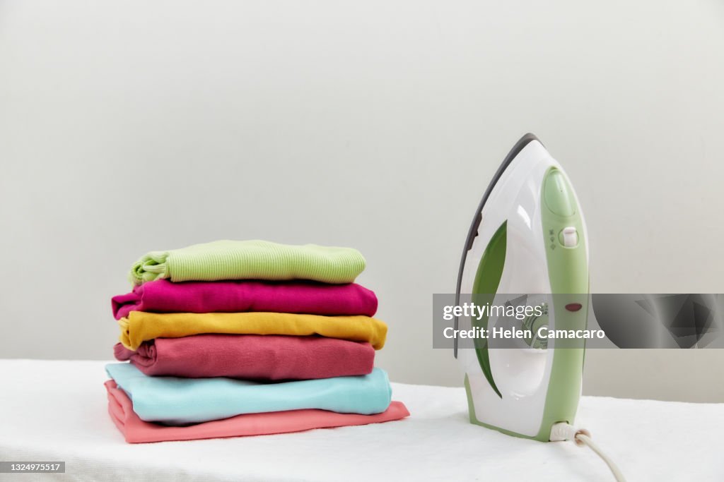 Steam Iron And Folded Clothes On Ironing Board High Res Stock Photo steam-iron-and-folded-clothes-on-ironing-board-high-res-stock-photo