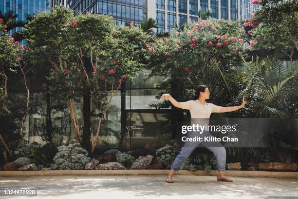 asian businesswoman practicing tai chi in the city - china balance stock pictures, royalty-free photos & images