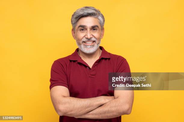 ritratto di bell'uomo maturo sorridente con attraversato isolato su sfondo giallo:- foto d'archivio - solo un uomo maturo foto e immagini stock