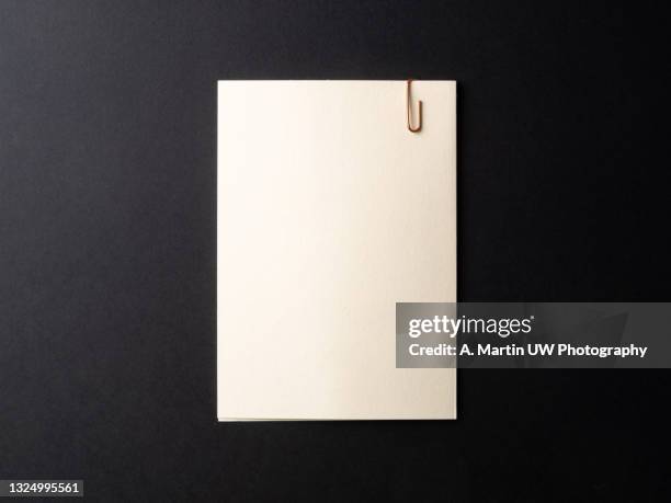 blank note with a paperclip on black background - note message stock-fotos und bilder