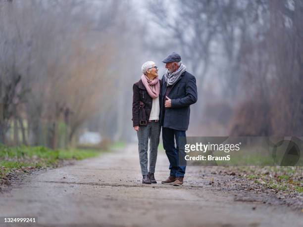 happy senior couple talking in winter day at the park. - mature couple winter outdoors stockfoto's en -beelden