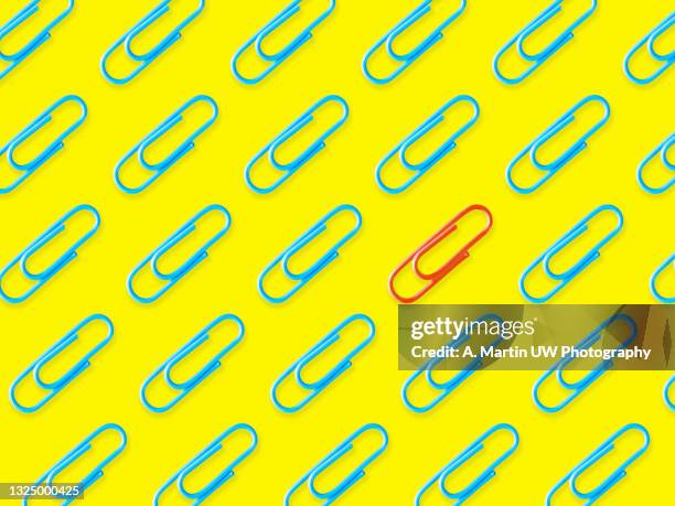 blue paperclips pattern with a red one between them isolated on yellow background. concepts. - paperclip bildbanksfoton och bilder