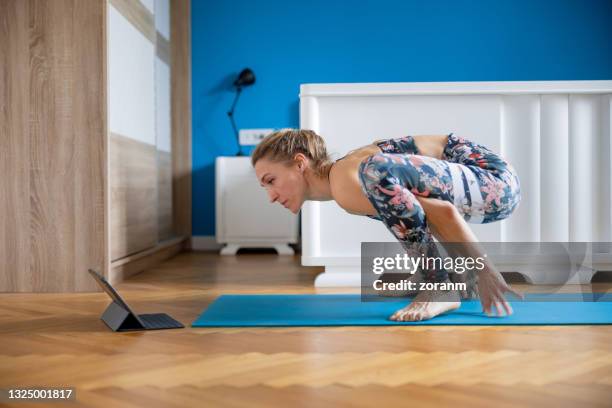 woman doing yoga at home in wagtail pose, looking at notebook - wagtail stock pictures, royalty-free photos & images