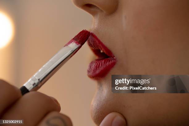 close up lipstick applied with small make up brush to lips - photo shoot makeup stock pictures, royalty-free photos & images