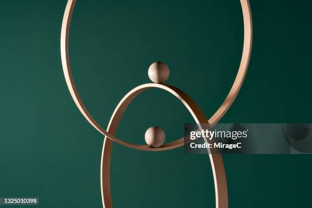 two wooden spheres moves on intersected rings - achievement gap stock pictures, royalty-free photos & images