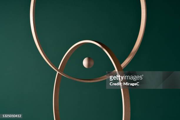 a wooden sphere in the center of intersected rings - focus concept stock-fotos und bilder